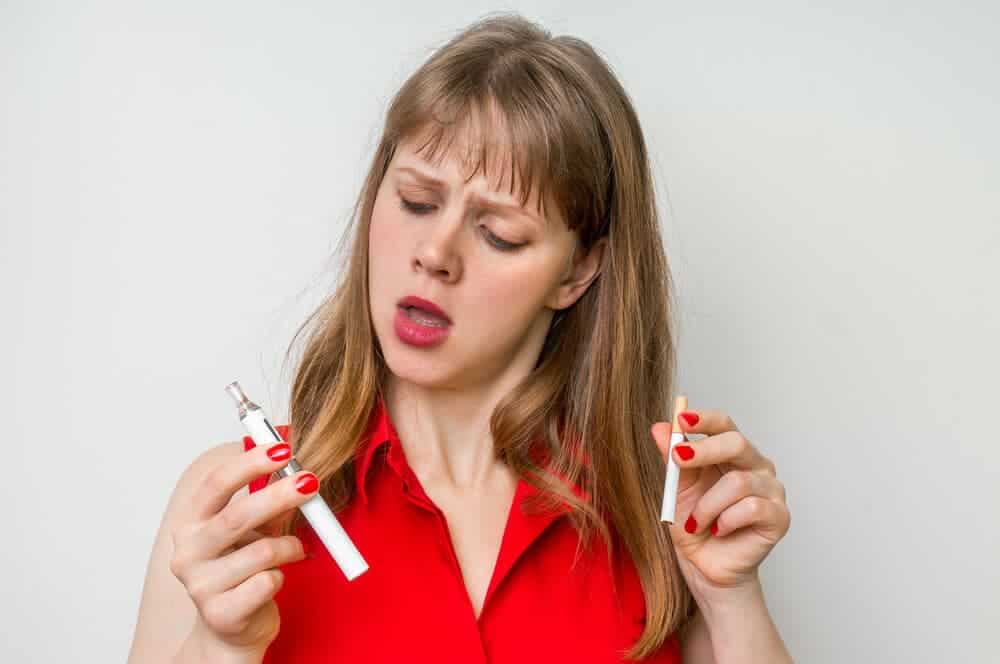 girl picking between a vape pen and a cigarette