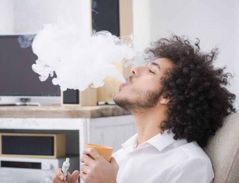 curly guy vaping on a couch